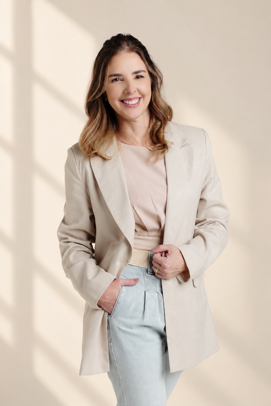 Anna Braga sorrindo, de blazer claro.